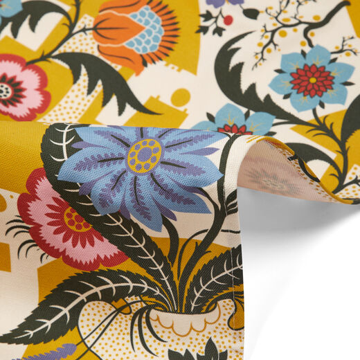 Detail of fabric depicting blue, red and yellow flowers on white and yellow background.